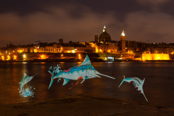 Maltese street artist Twitch create a spectacular light painting, depicting a swordfish leaping from of the waters surrounding Valletta while being consumed by humans. Twitch, in collaboration with Our Fish and Dancing Fox and has created the artwork to send a message to 20017 Our Ocean conference delegates that they must help protect Mediterranean sea life. Photo: Dave Walsh Photography